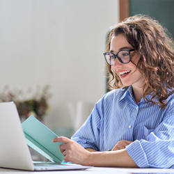 Lady smiling whilst reading from a laptop screen