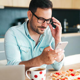 Man in the kitchen planning on his mobile phone