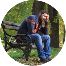 Person sat on a park bench with hand supporting their head