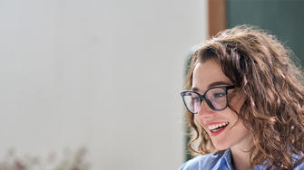 Lady smiling whilst reading from a laptop screen