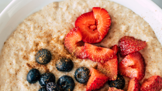 A bowl of porridge with strawberries and blueberries
