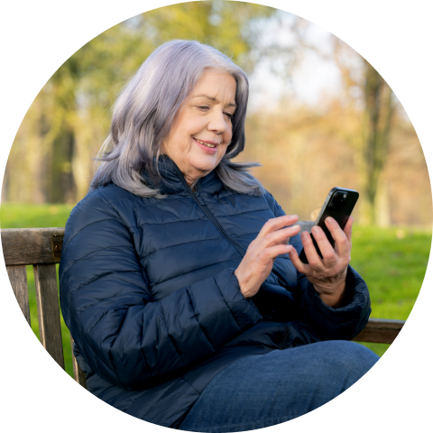 Image shows a person sitting on a bench holding a smartphone with the Accu-Chek SmartGuide app.