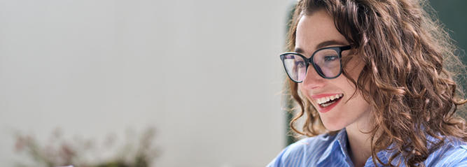 Lady smiling whilst reading from a laptop screen