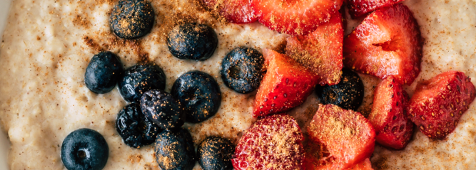 A bowl of porridge with strawberries and blueberries
