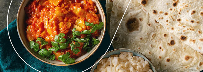 A bowl of vegetable curry with a side of basmati rice and naan bread. 