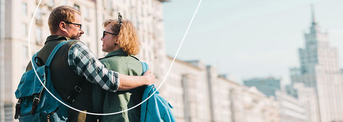 A couple, seen from behind, embrace on a city street.